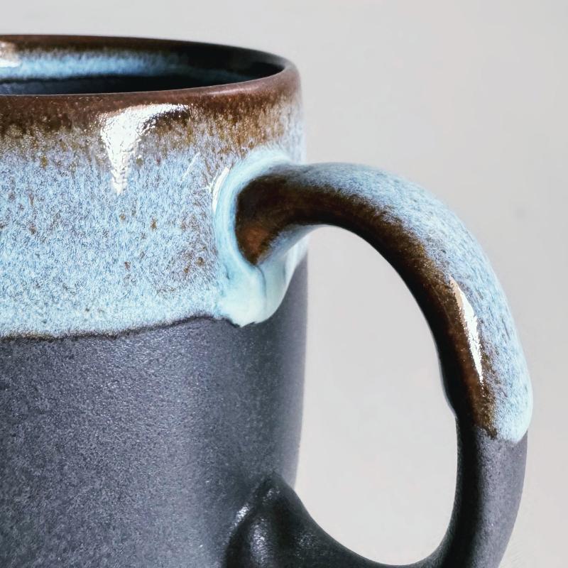 A handle of a handcrafted large porcelain TOKA mug in black with a large handle. Made in Japan.