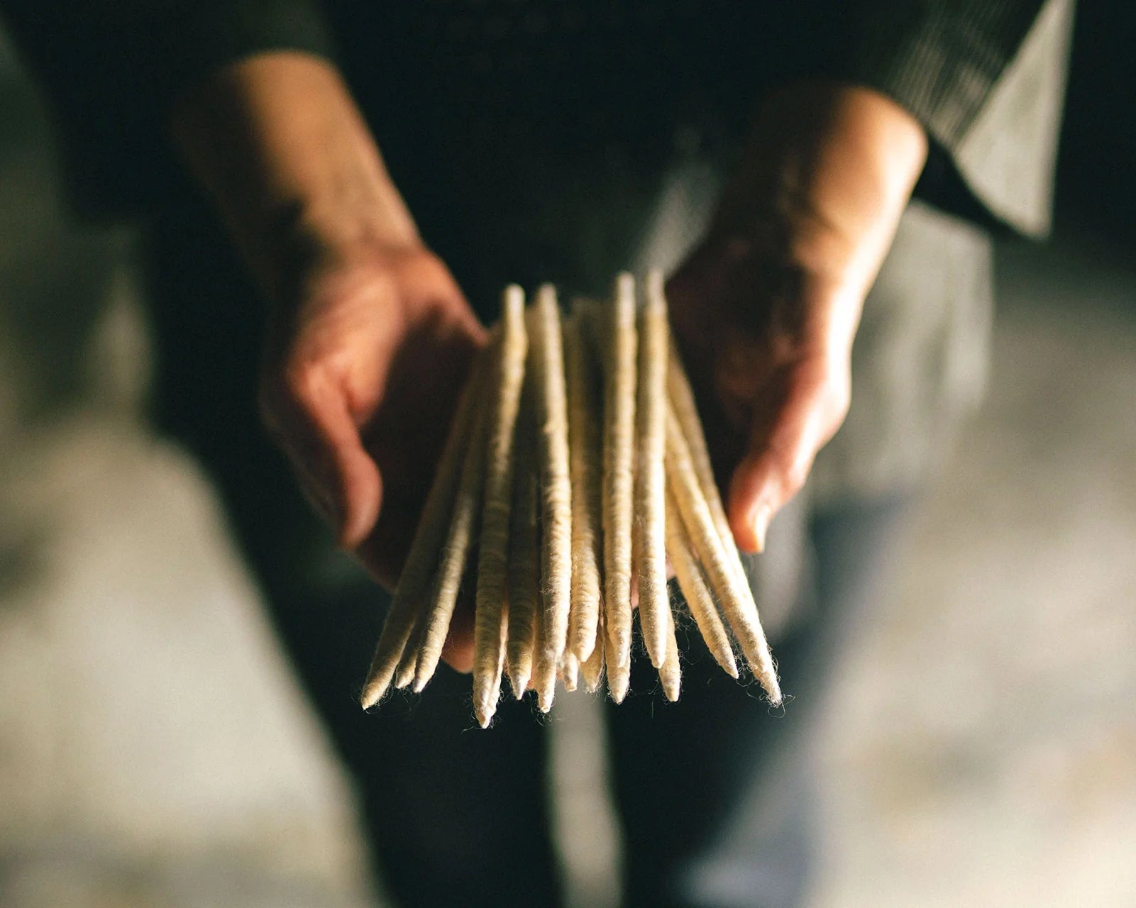 Person holding a stack of Japanese candle wicks against a blurred background