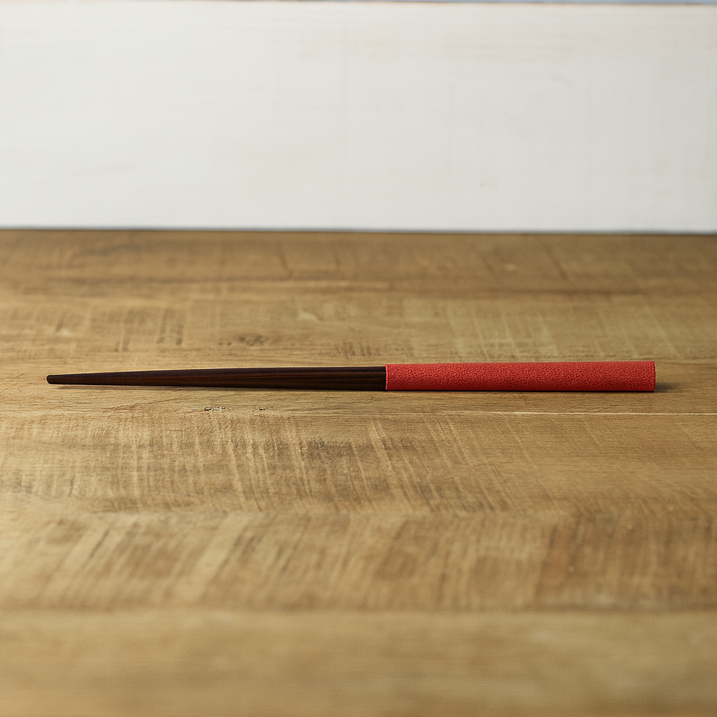 Chopsticks with red ferrule and black tips on a wooden surface
