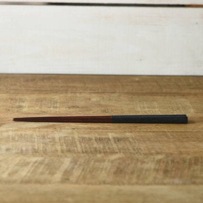 Wooden stick on a wooden surface with a white wall in the background