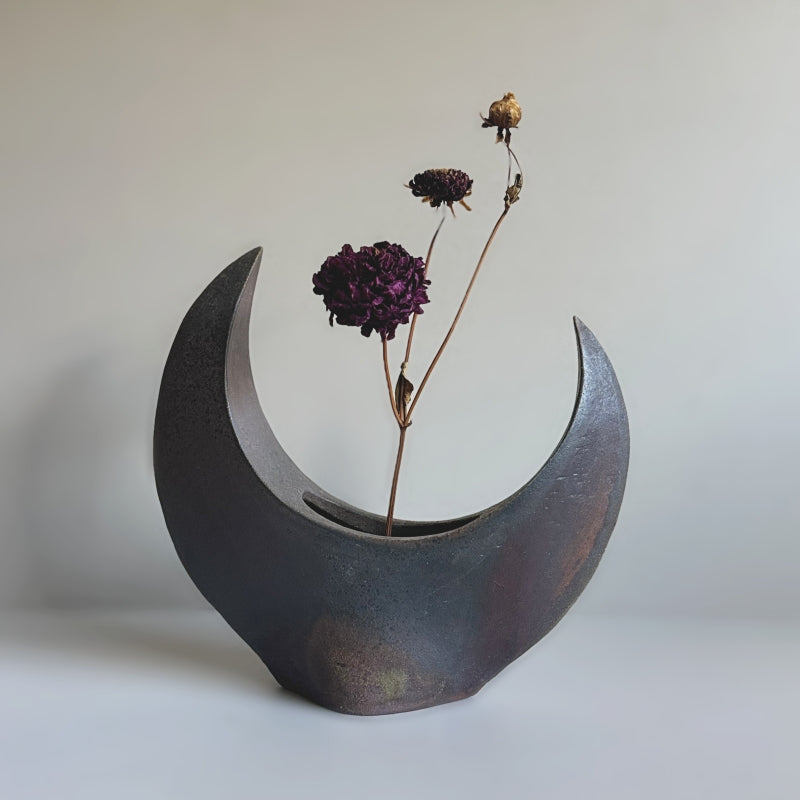 A handcrafted Crescent Vase made by Tsugaru Kanayama Pottery in Japan, featuring a unique crescent moon shape and dark earthy tones.