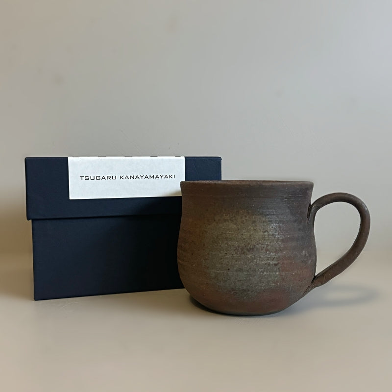 A rustic, handcrafted ceramic mug with a round shape and an earthy, textured surface, featuring shades of brown and gray, made by Tsugaru Kanayama pottery in Japan.