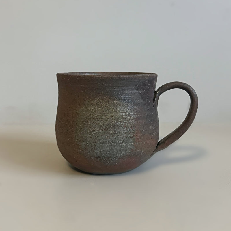 A rustic, handcrafted ceramic mug with a round shape and an earthy, textured surface, featuring shades of brown and gray, made by Tsugaru Kanayama pottery in Japan.