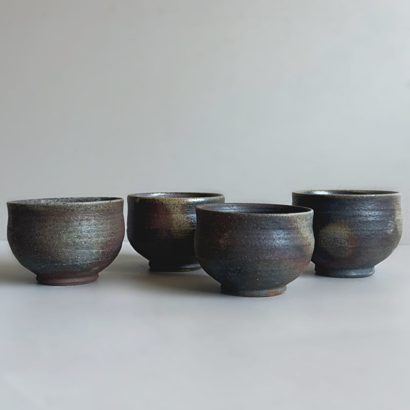 a handcrafted Tsugaru Kanayama pottery sake set made in Japan, featuring a dark earthy brown finish. The set includes two sake cups and a traditional sake bottle.